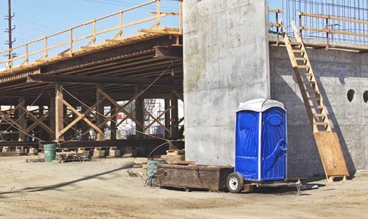 a row of blue portable restrooms set up on a work site